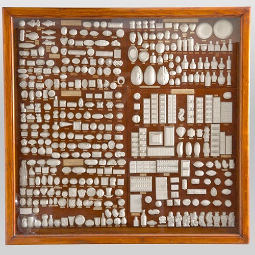 Chocolatier`s Moquettes (Master Moulds) in a glass-fronted display cabinet, Belgium, c1950 suitable for table or wall mounting.<br />
<br />
If you look carefully, you can actually see the small imprints of some of well known chocolates and their