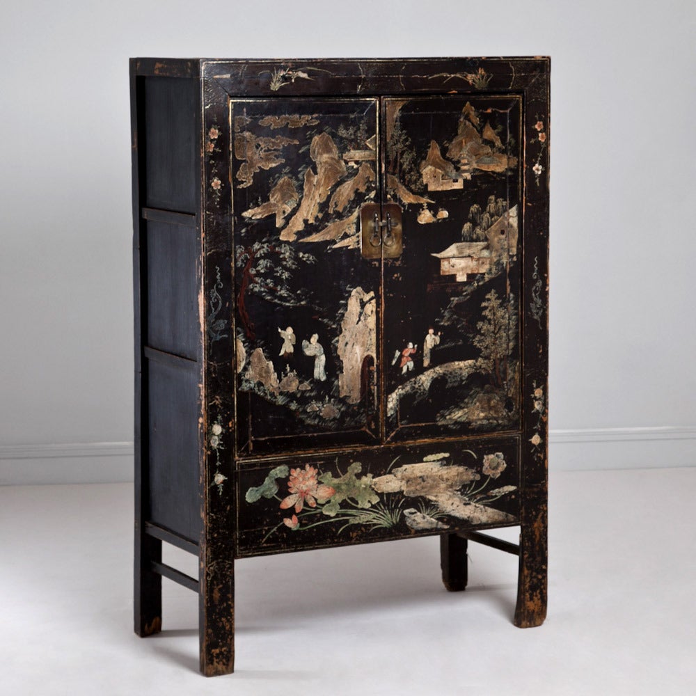 Early 19th century two-door lacquered Chinese cabinet decorated with Chinese pastoral scenes and floral motifs. Complete with brass handles and latch. The interior is simple with three shelves.

Due to its age the exterior has suffered wear and