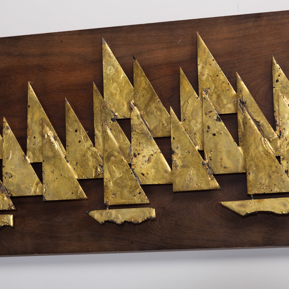 A rare brass metal sailboat wall sculpture by Peter Pepper mounted on a wooden backdrop, 1960s