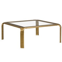 A  Square Brass Coffee Table with Glass Top and Curved Cor