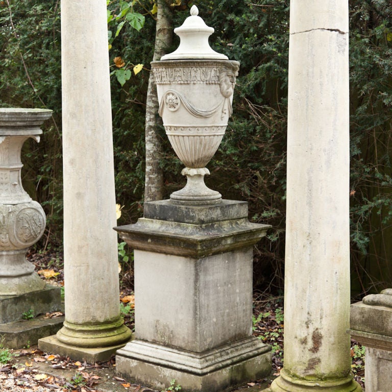 A Pair of Bampfylde Style Composition Stone Lidded Urns on Pedestals