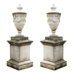 A Pair of Adam Style Composition Stone Lidded Urns on Pedestals