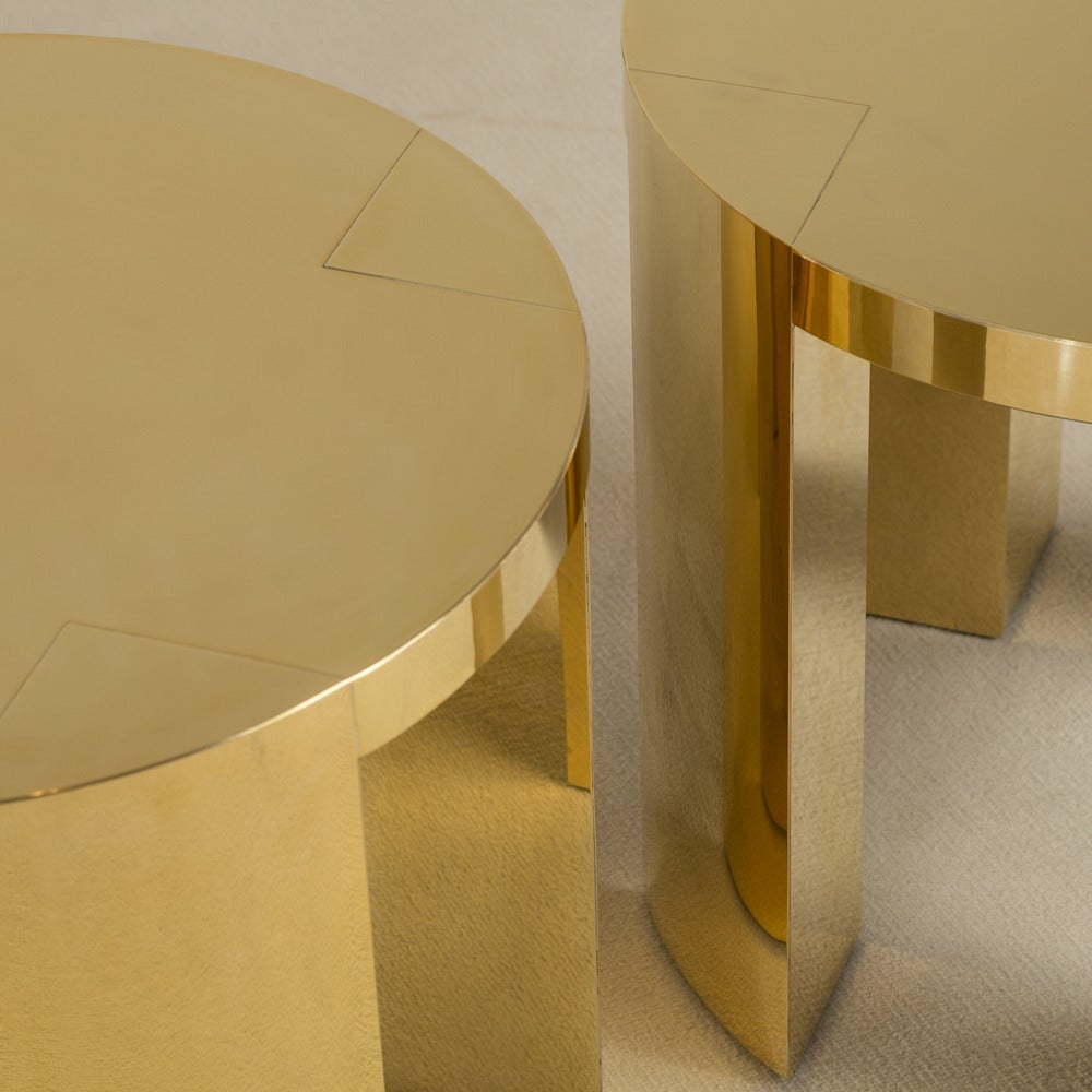 A pair of polished brass-wrapped circular side tables by talisman bespoke.