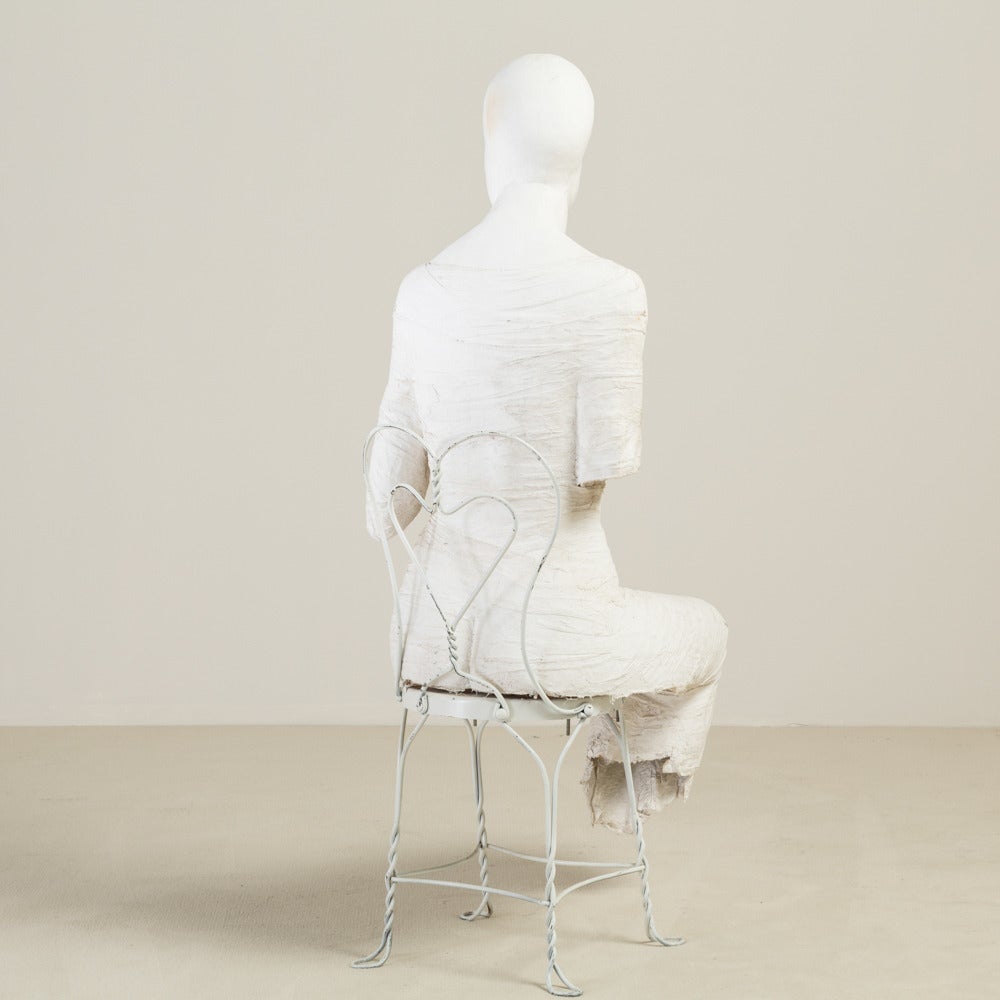 A large plaster floor sculpture theatrically showing a seated figure on a wire framed chair, 20th Century