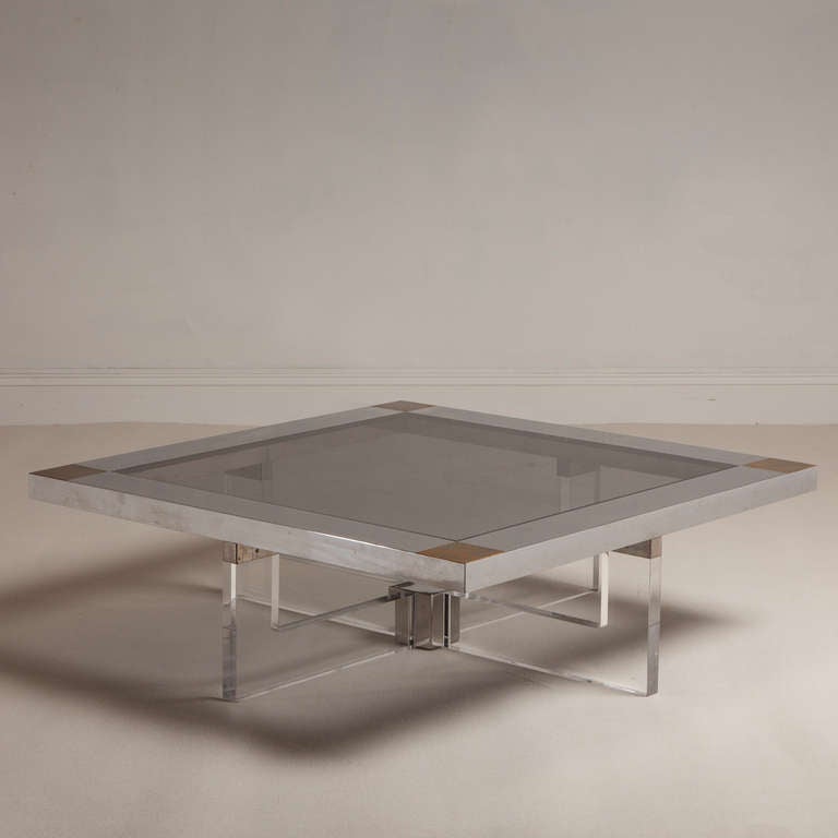 Large Lucite cross based coffee table supporting a chrome square top with brass corners and inset with a tinted glass, 1970s.