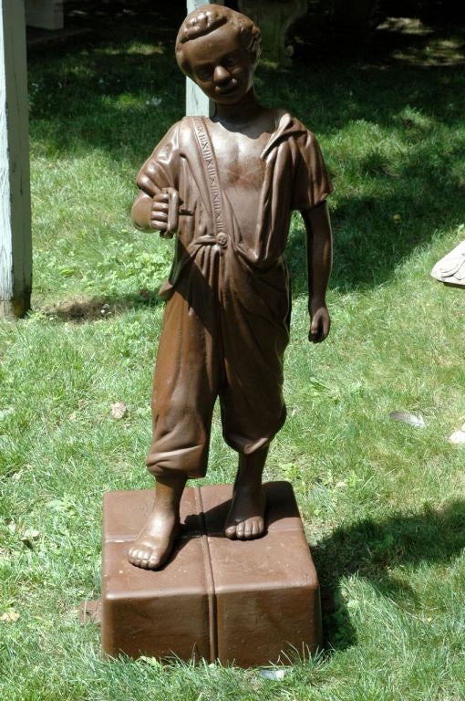 American, early 20th century, cast iron lawn jockey depicting a youth standing on a box. This is one of the three original versions of the lawn jockeys. Original they were created in the late 18th century primarily as a horse hitching post, later