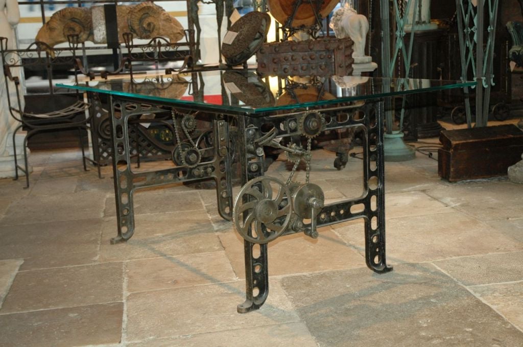 American, Industrial cast iron table base with original gears and pulley mechanisms complete with a new glass top measuring 3 feet by 6 feet.  Excellent as a desk or as a dining table.