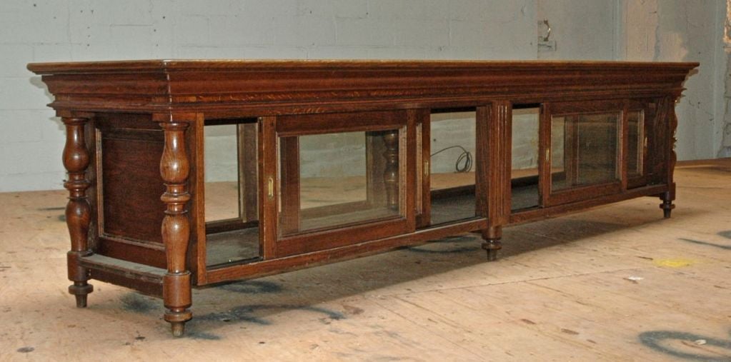 French, circa 1880, oak store fixture in excellent condition.  It has 4 glass panels on the back which slide on ball bearings to enable access to the display. On the front it has 4 matching fixed windows. Excellent example of solid craftsmanship and