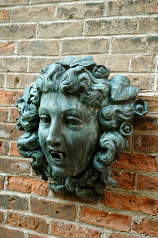 American, 20th century, cast bronze fountain mask depicting a woman with beautifully detailed curly hair with roses and a garland.
