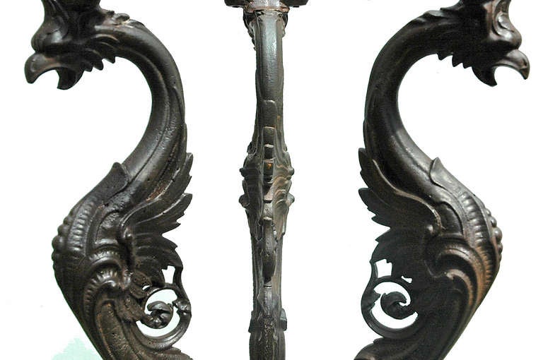 Cast iron 3 legged table with unique legs featuring griffins with claw feet and open mouths.  Will accept round marble or glass top of 24 to 36 inches.