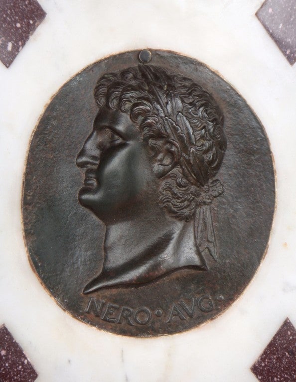 A Grand Tour Marble Plaque with a Mounted Bronze Head of Nero.
The statuary panel inlaid with Egyptian porphyry is set within the original ebonised frame with giltwood inner and beading.
