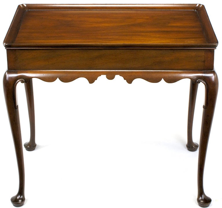Well crafted side table by Kittinger of Buffalo, NY. Regency styling with a curved and scalloped apron, cabriole legs and full galleried top with incised corners. Unique characteristic is the double pull-out writing or drink surfaces.