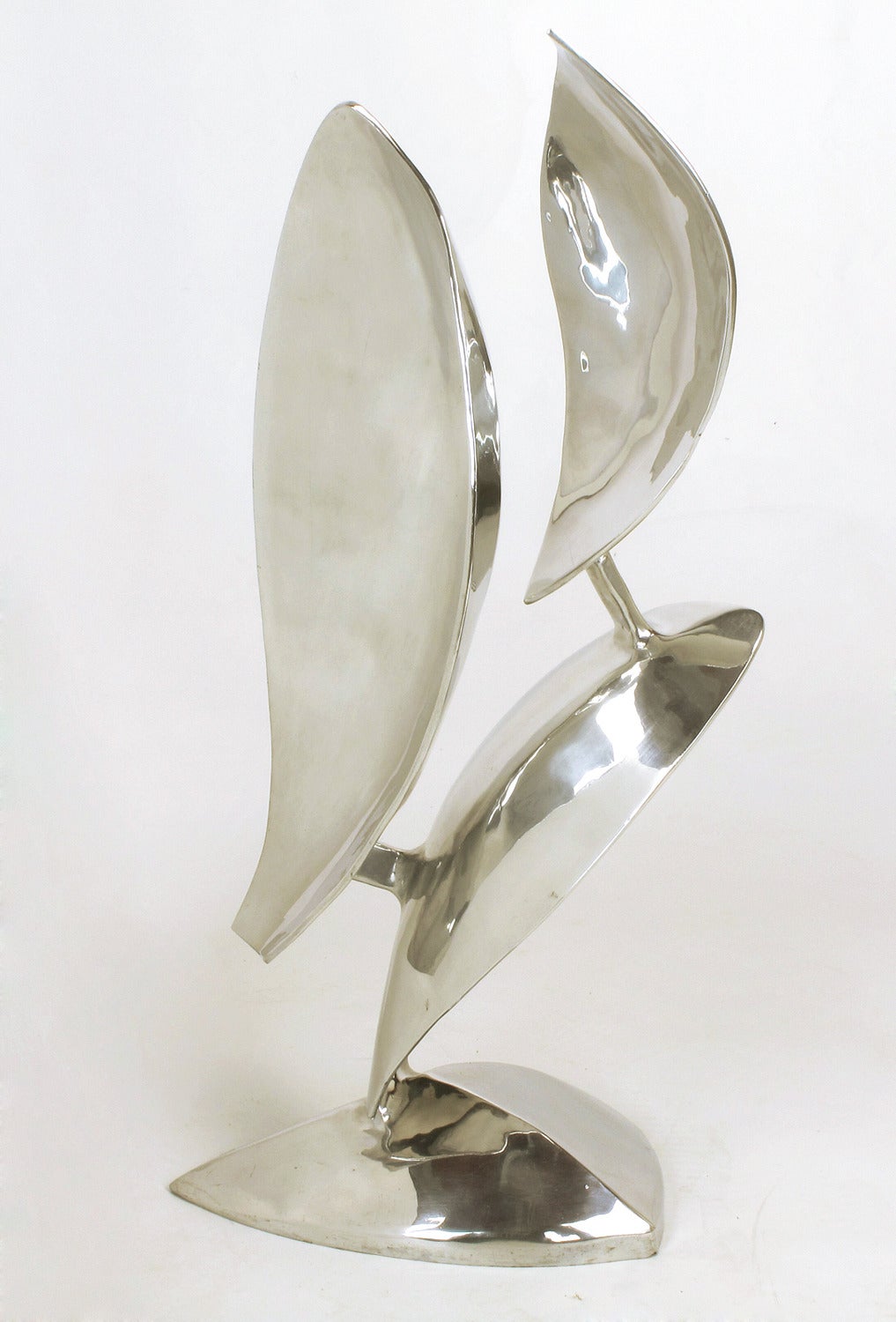 Polished aluminum sculpture of three organic shapes, possibly leaves or flower petals, mounted on a pyramidal base. Signed and dated 1977. Measures: 36