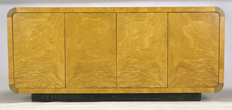 A striking burled olive wood and Macassar ebony radiused corner sideboard cabinet from Henredon's Scene Two collection. Four cabinet doors open to reveal a pair of drawers and four shelves. Plinth base of ebonized oak.