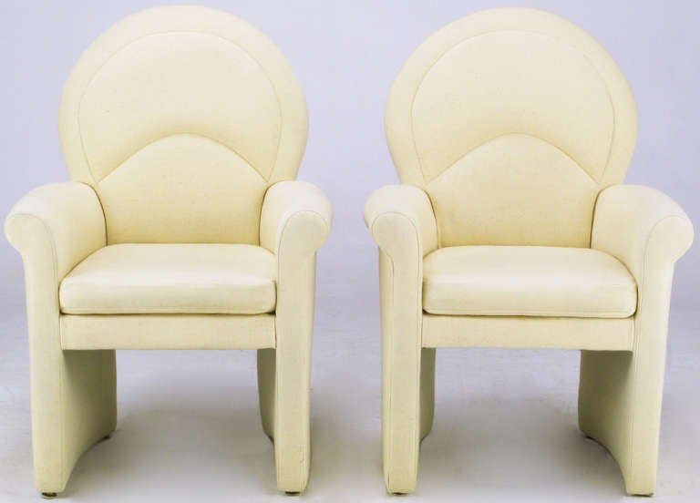 In the manner of Donghia, pair of ivory wool fully upholstered club chairs. Rolled arms, curved panel sides, loose seat cushions with arched back with tufted detail. Would also make very elegant dining room head chairs.