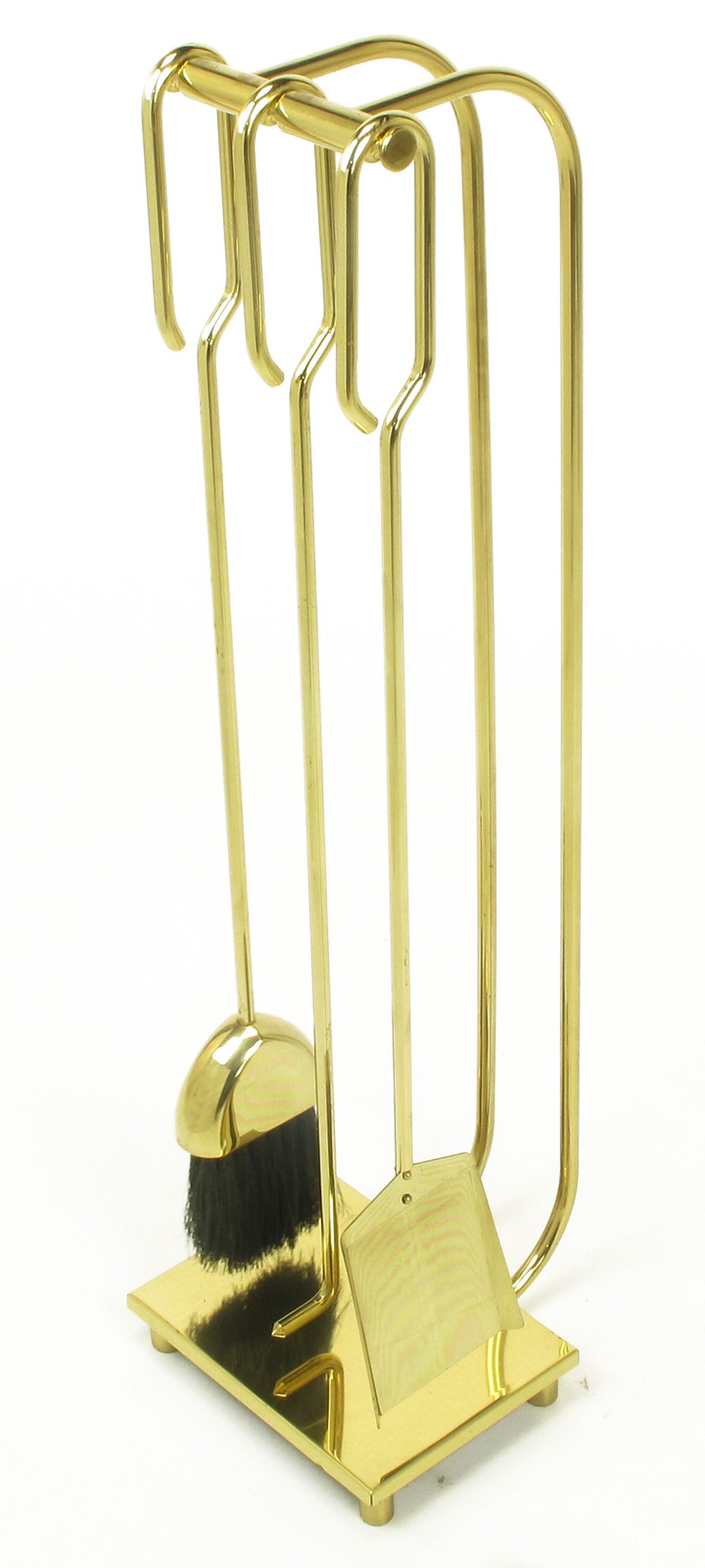 Set of three tools in brass with open end hooks; shovel, broom and angled poker. Hung on brass double curved posts with a brass incised bar and brass plinth base.