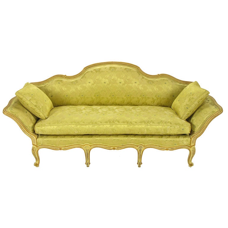 With its fluid lines painted and gilded, the frame of this lovely sofa has a wonderful patina. Upholstered in a celadon floral damask with down cushions.