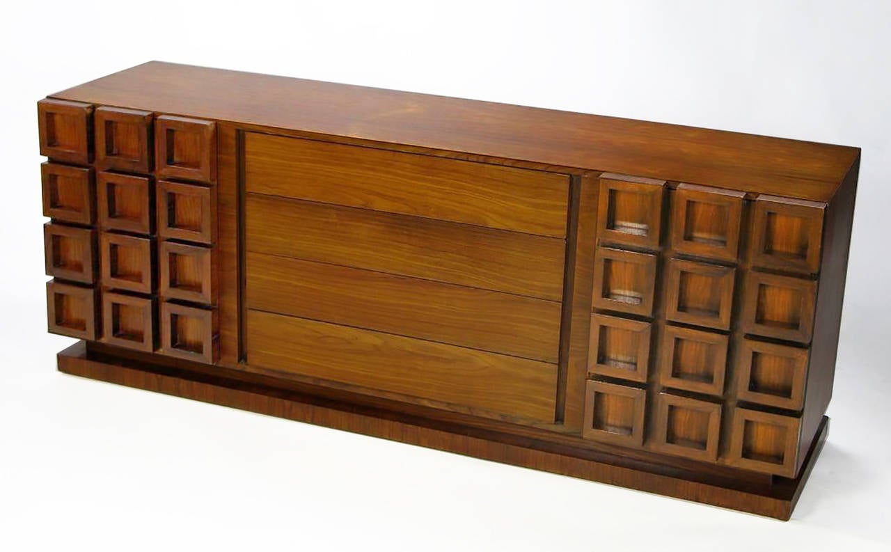 Uncommon walnut cabinet from revered furniture company and former Baker Furniture subsidiary, Peck & Hills. The central four drawers are faced in solid walnut. Behind the left door are four more drawers, and the right door conceals open storage.