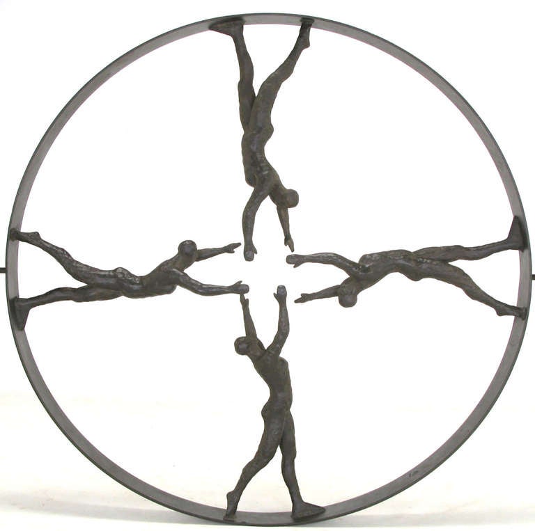 Striking and large circular iron wall sculpture with four men with outstretched arms at the center. Each man is placed at a ninety degree angle to the previous man creating a center star pattern of hands and arms. Well cast and heavy, the iron discs