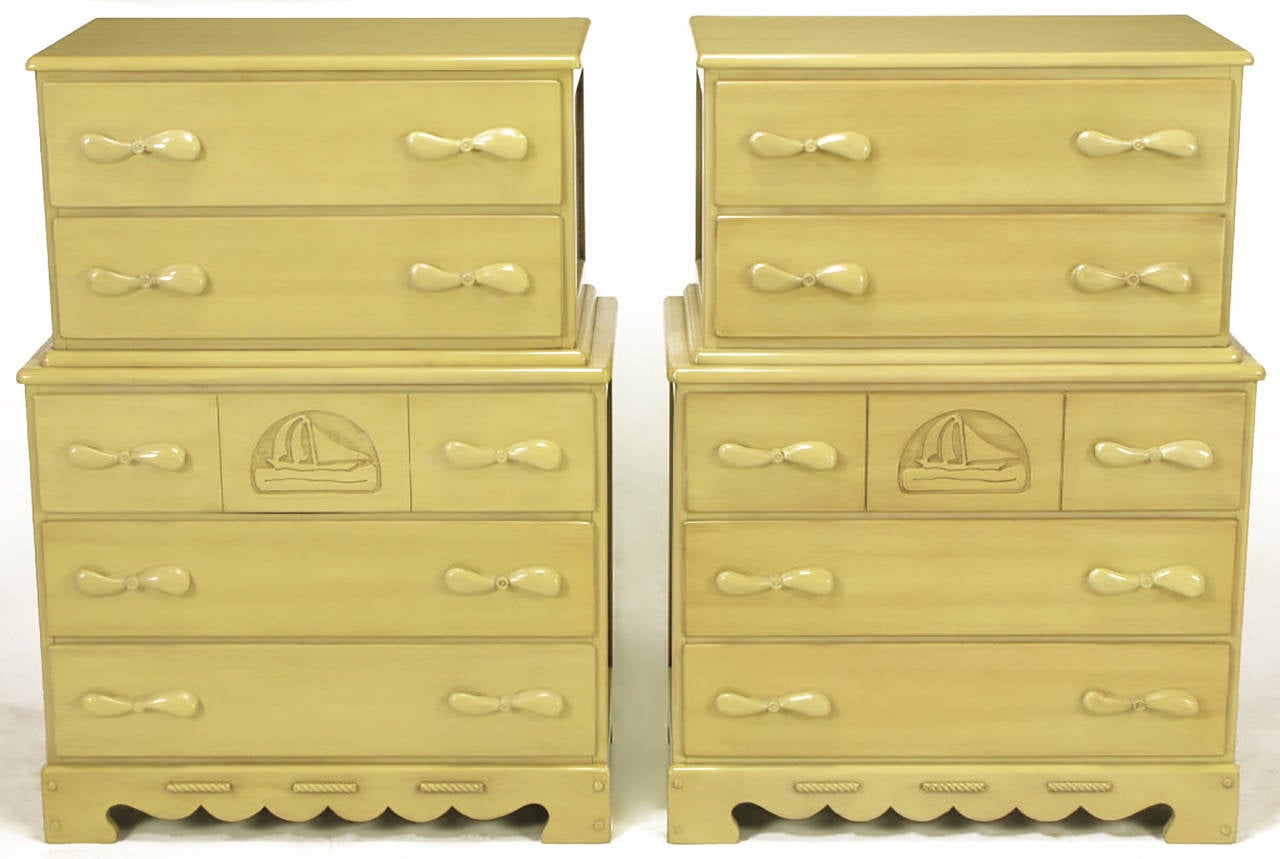 Glazed and hand-carved maple five-drawer tall chests with propeller-form pulls and carved reliefs of cutter sailboats. Open carved plinth base resembles waves of the ocean. Light sage color, with the grain of the wood visible. Perfect for a boy's