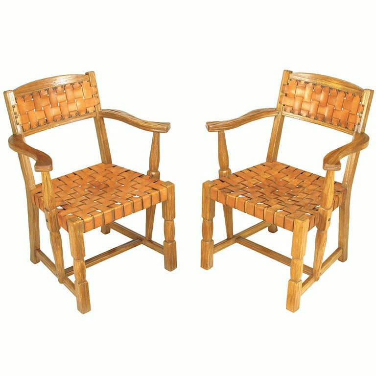 Pair of rustic white oak arm chairs with woven umber leather strap seats and backs with brass nailhead upholstery tacks. Attributed to A. Brandt, Ranch Oak Furniture.

A. Brandt Ranch Oak Furniture was made for nearly fifty years in Fort Worth,