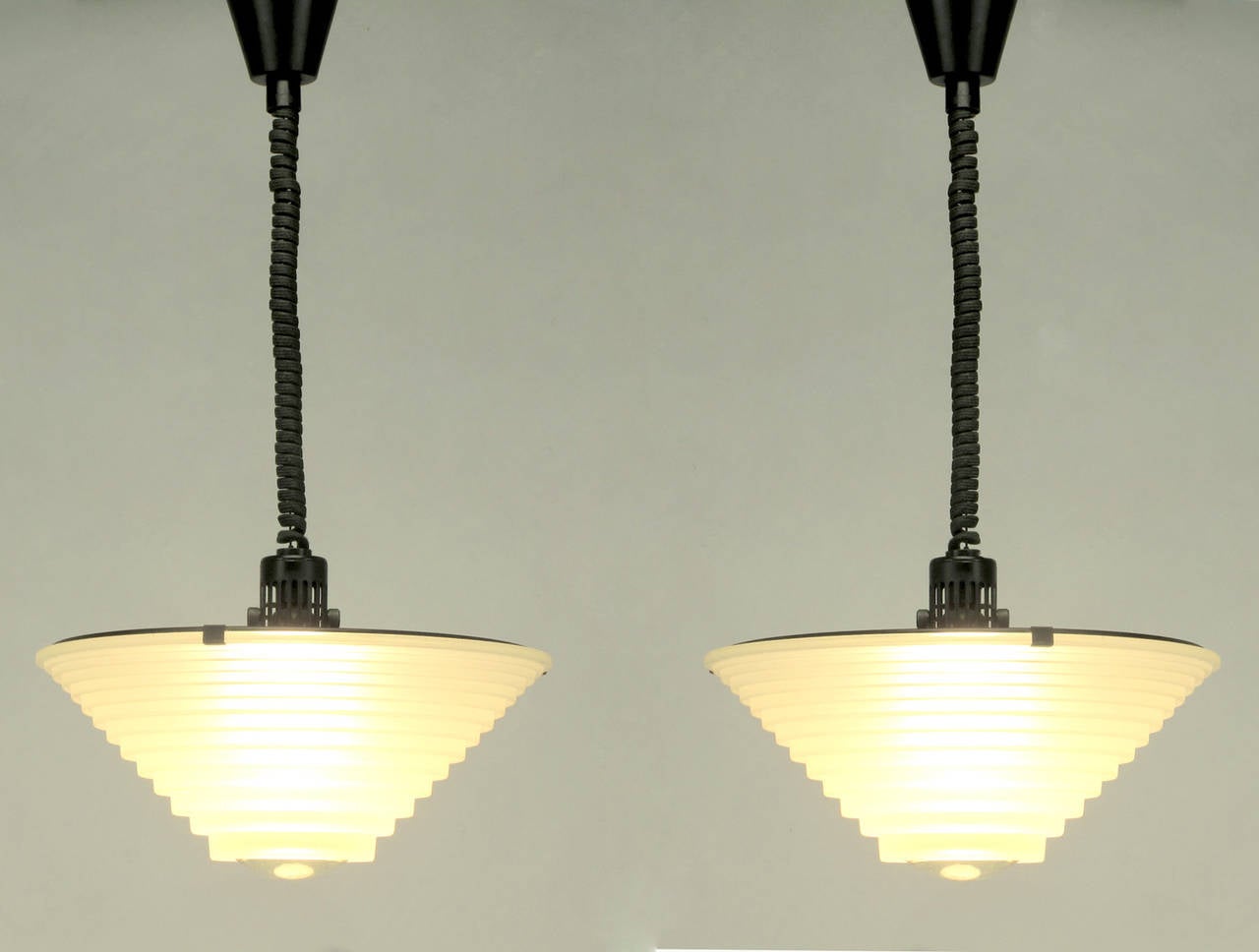 Art Deco meets Industrial in this pair of pendant lights by Angelo Mangiarotti for Artemide, Italy. Satin black metal disc fitters with white underside and sandblasted thick graduated glass shades with magnifying centre lenses. Each light has an