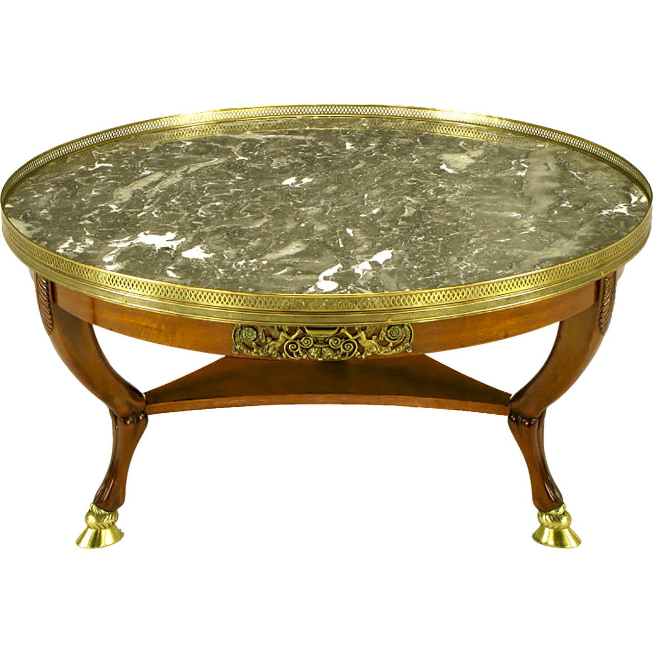 Empire style coffee table with bronze cloven hoof feet and bronze appliques. Stylized trio of quadruped hind legs with cycad leaf detail. Reverse trefoil lower shelf support, and gray marble top with pierced brass gallery.