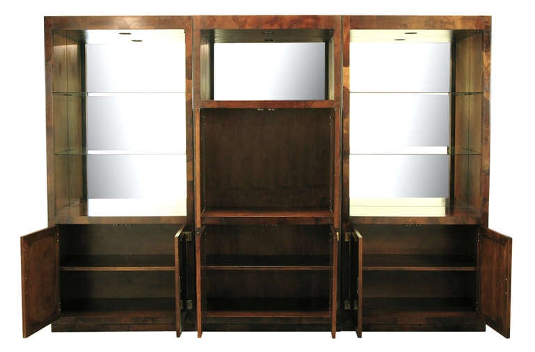 Exceptional three-piece oyster burl Campaign wall unit by Hekman Furniture. Two outer cabinets feature open glass shelving with mirrored backs and a two door lower cabinet with single shelf. The centre unit features a pair of two-door cabinet