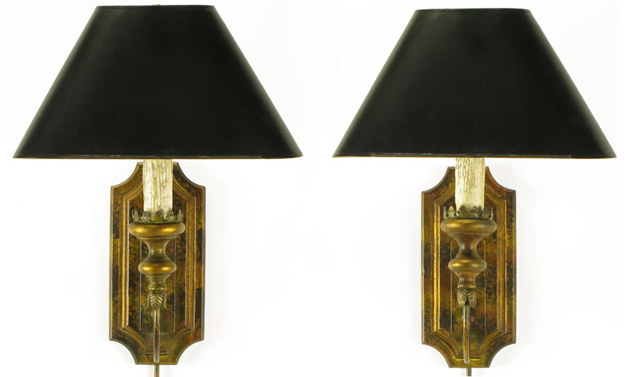 Beautiful pair of Renaissance Revival candle style electric sconces with black oval shades, parcel-gilt carved wood back plates, and brass tubes to conceal electrical cord when wired for wall outlets.