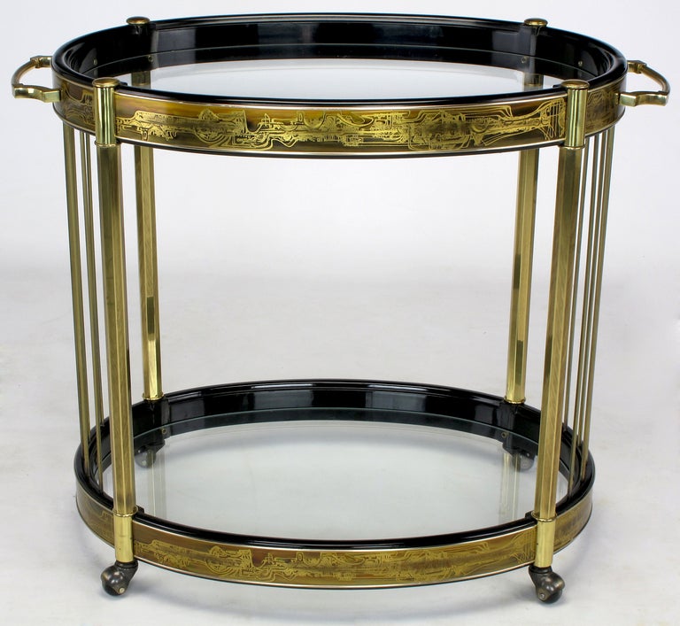 Black lacquered and acid etched brass wrapped oval bar cart by Mastercraft. Patinated brass legs and polished brass rods support the glass bottomed serving areas, which are wrapped in Bernhard Rohne acid etched panels. Solid brass pulls and original