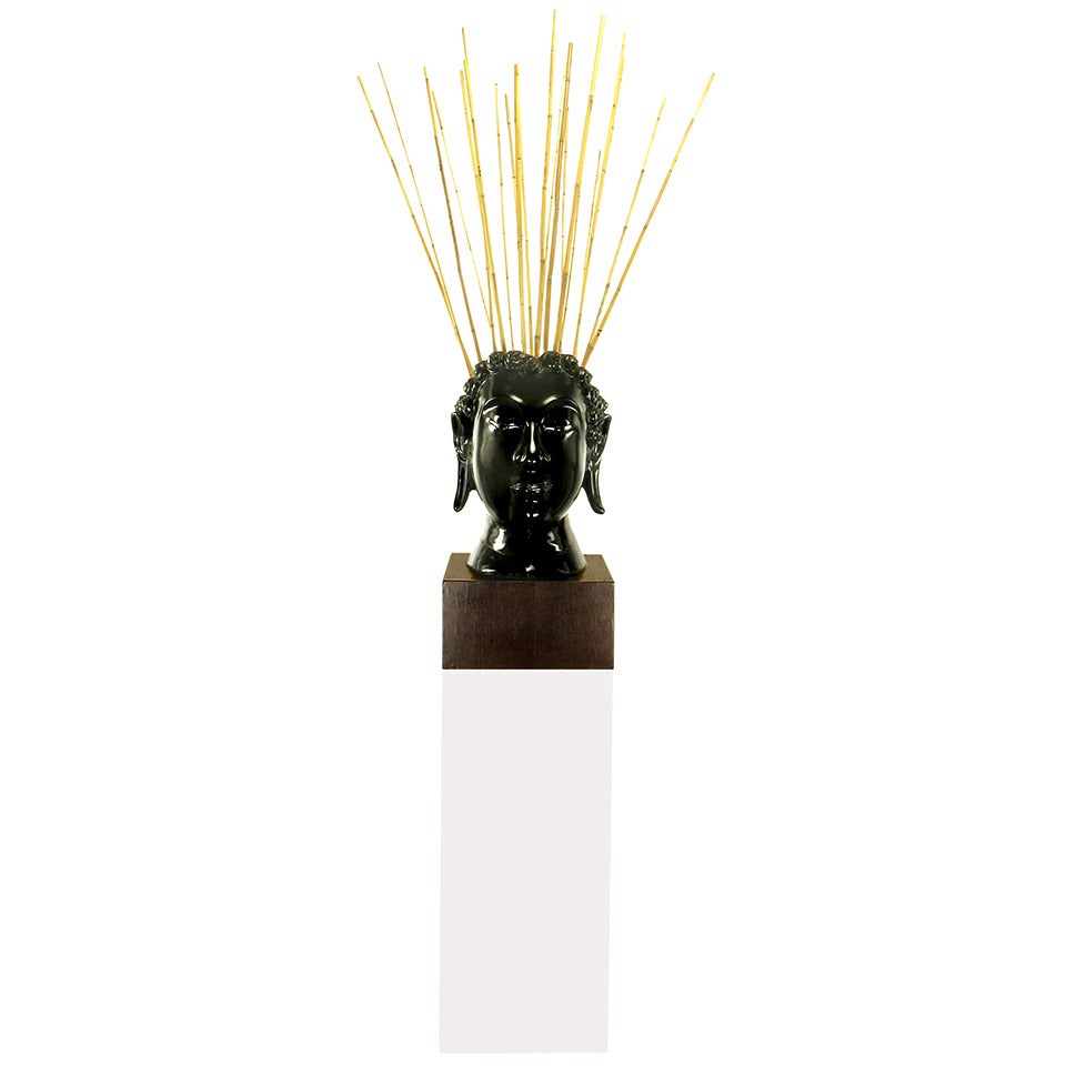 Busto de Buda de caoba tallada y lacada en negro sobre zócalo de caoba con pedestal de Lucite blanco. La parte posterior de la cabeza está abierta y puede utilizarse de forma creativa. En este caso, es como recipiente para tallos de bambú.

Sólo