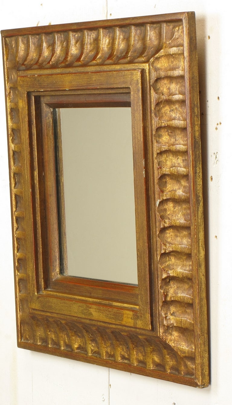 Circa 1960s carved and gilt wood mirror by La Barge Mirrors Inc. Holland, Michigan. Spanish revival style mirror with primitive carving and distressed gilt over red bole. The 17
