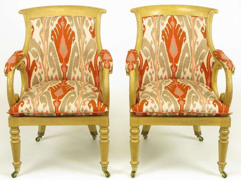 Pair of Regency armchairs with factory distressed wood frames and cotton/silk blend ikat print upholstery in white, taupe grey, persimmon and rose. By Interior Crafts of Chicago, IL. Scrolled and padded arms with curved upholstered backs and loose