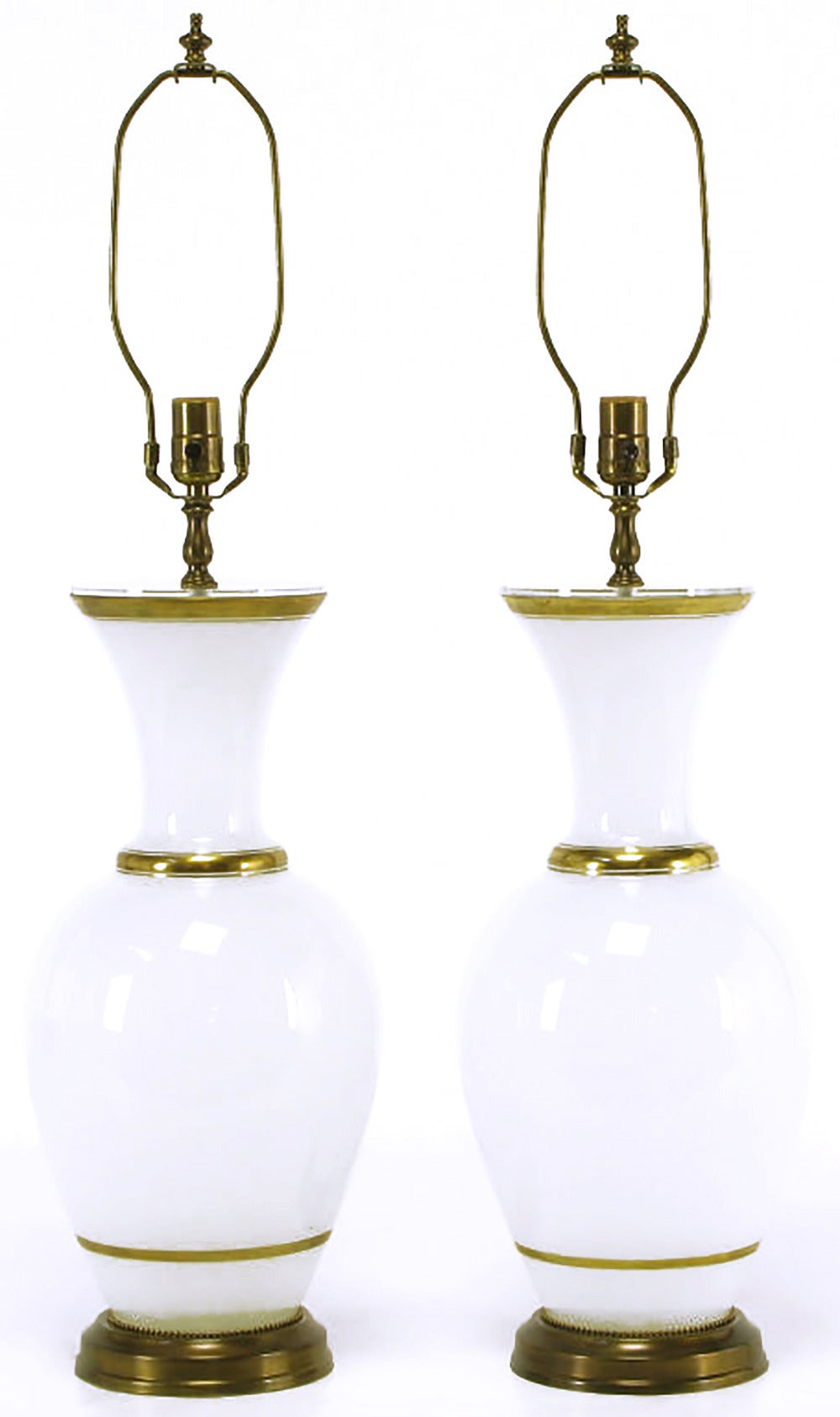 Pair of vase form milk glass table lamps with gilt banding and brass bases. Unexpected Lucite vase cap fitted to the top of the lamp bodies. Brass stem, harp and socket.