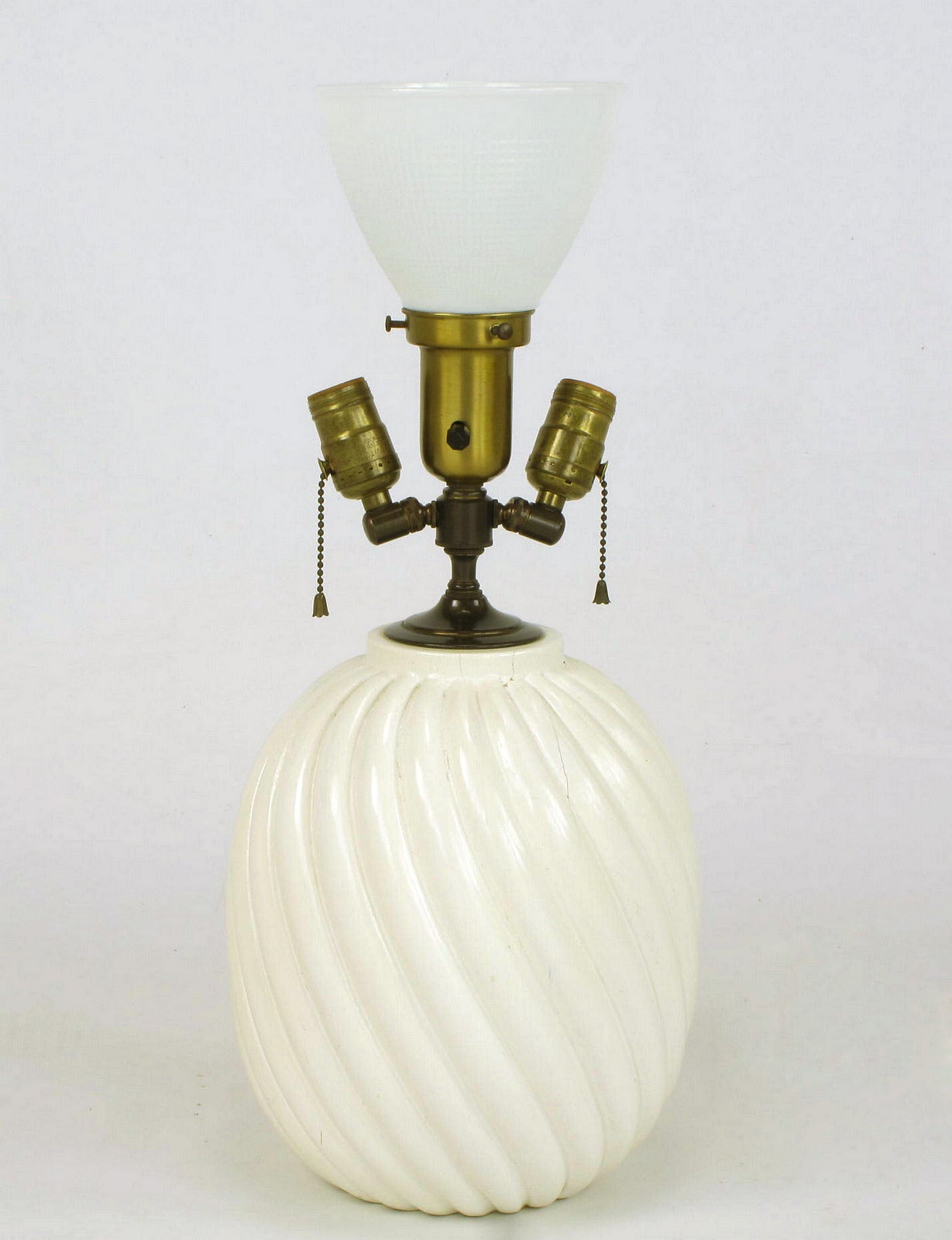 Uncommon spiral carved table lamp constructed of solid wood with an off-white gloss lacquer finish. Three brass light sources with a center milk glass diffuser and side adjustable sockets. Sold sans shade.