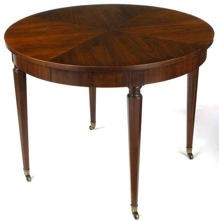 Well made and beautifully grained round parquetry top regency dining table by Kindel Furniture. Tapered hexagonal legs finish with brass sabots and casters. Extends to 86
