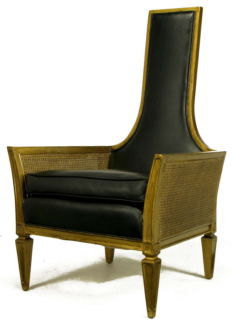 Moorish style tall back lounge chair with an ebony glazed gold lacquer frame and cane sides. Upholstered in high quality black leather-like Naugahyde. Loose seat cushion and fixed back.