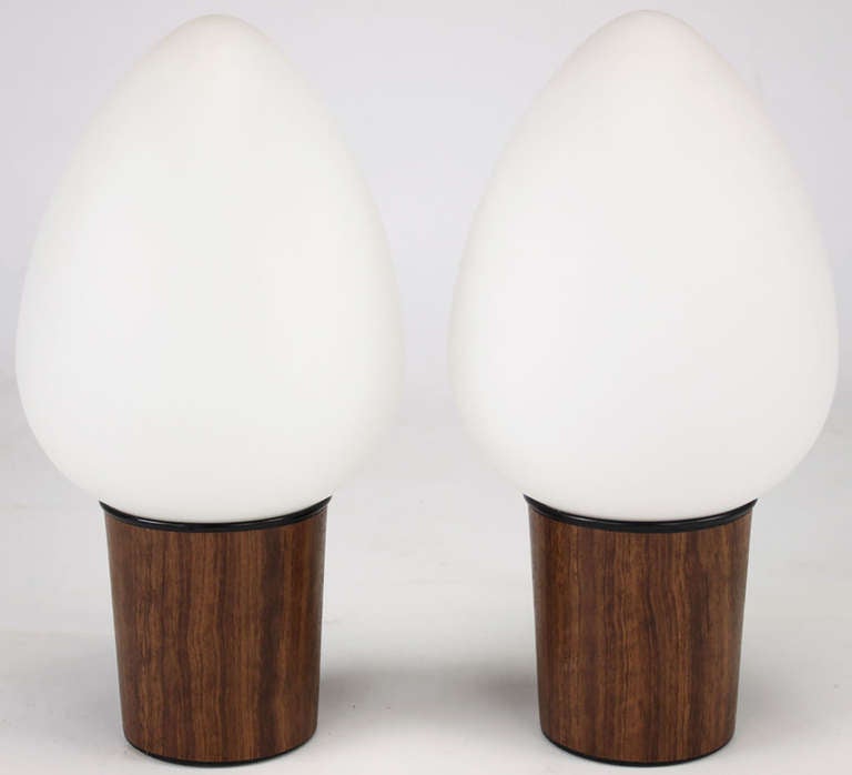 Pair of petite egg shade lamps surmounted on laminated wood grain metal cups with black lacquered rims.