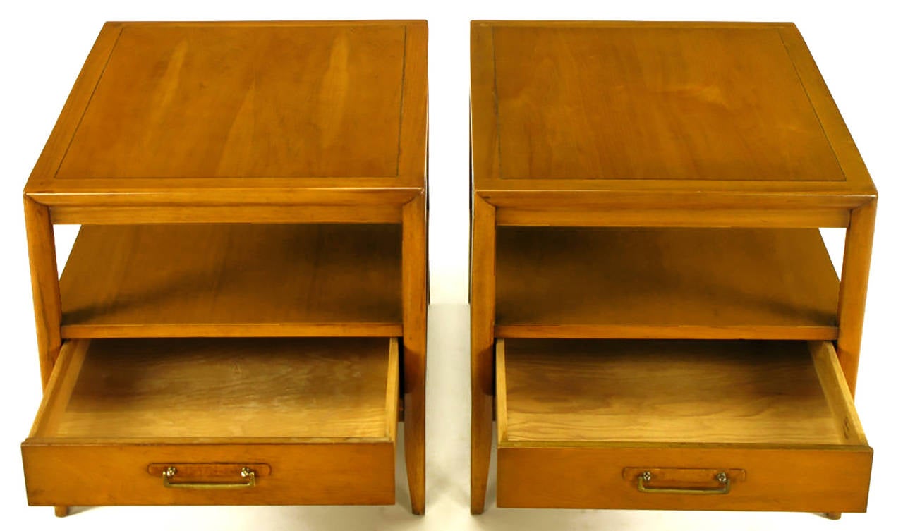 Pair of bleached walnut and mahogany two-tier end tables with lower drawer by Drexel. Recessed apron and drawer casement, tapered legs and incised bordered top. Burled olivewood escutcheon with brass drop U-pulls. Finished on all four sides. Turned