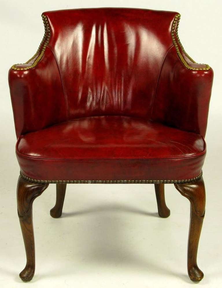 Upholstered in beautifully aged deep red claret leather, these armchairs were made by S.J. Campbell Co., a venerable furniture maker in Chicago history. Vertically rolled arms, cabriole legs, and brass nailhead trim.