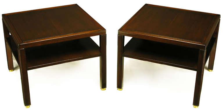 Pair of Edward Wormley for Dunbar Classic design two-tier end tables. Solid mahogany legs with raised panel and unexpected recessed brass disc feet. Solid mahogany top border with mahogany raised plateau top.