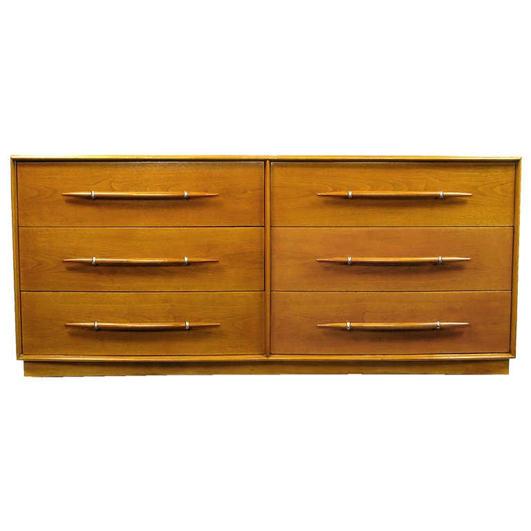 Iconic double bow front six drawer long dresser by Robsjohn-Gibbings is in beautiful original condition, very well preserved. The silver plated mounts that anchor the tusk shaped wood pulls are a rare variation of the more often seen silver end