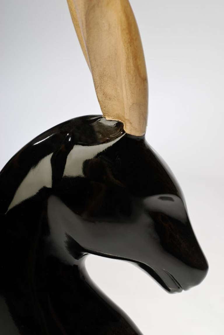 Surmounted on a Lucite base, this striking sculpture depicts a gazelle with art deco stylizing. The neck and head are richly finished in many coats of black lacquer, and the corkscrew horns, or antlers, created from bleached wood.