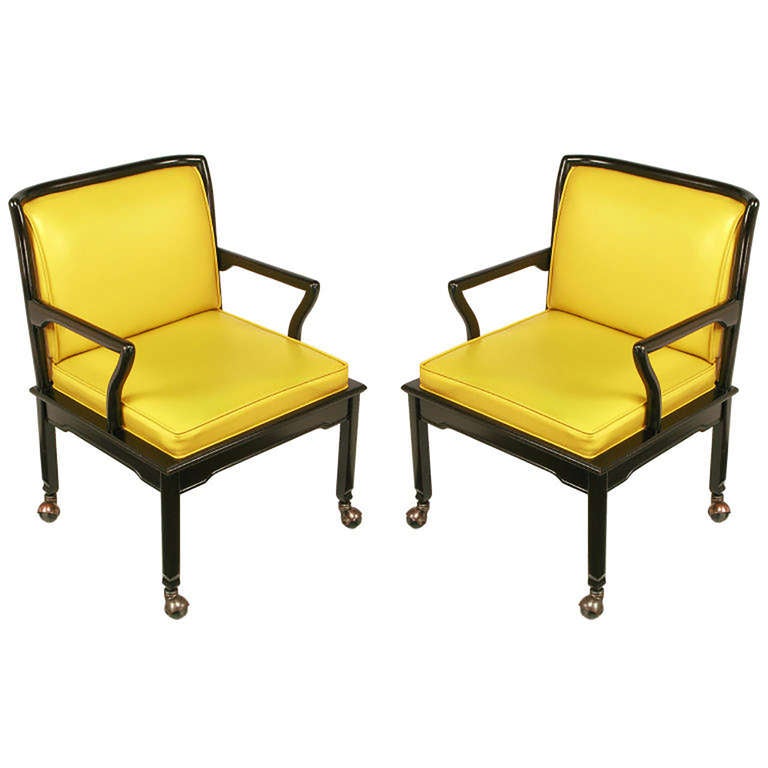 Pair of Widdicomb ebonized mahogany and saffron leather-like upholstered chinoiserie lounge chairs. Good sized seats with ample room on padded seat cushion. Curvaceous back frame and arms. Original patinated copper covered casters. Can work as head