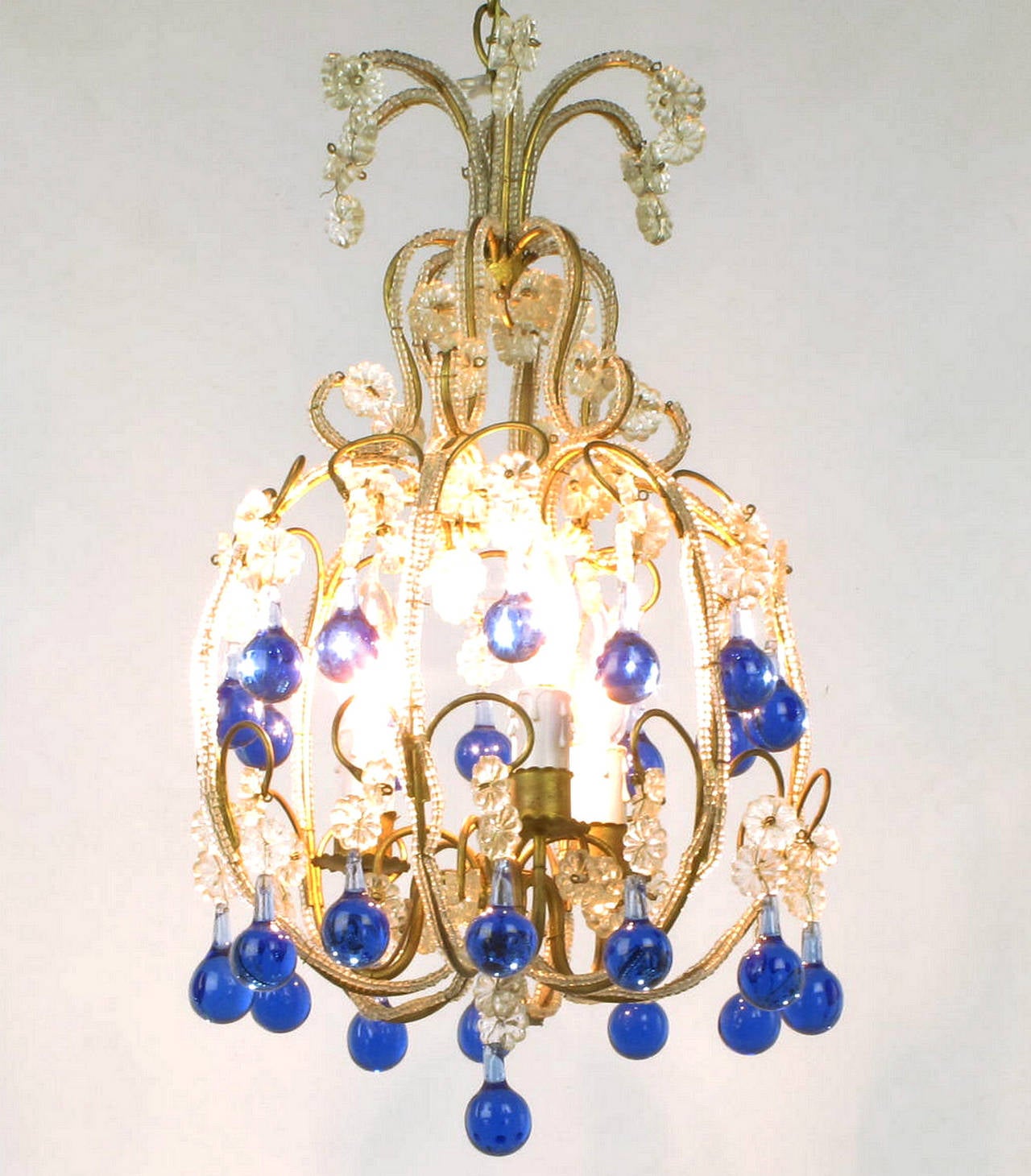 Italian gilt metal and beaded crystal chandelier, circa 1940s. Beading runs along both sides of the gilt metal frame with rosettes and blue Murano tear drop crystals at each filigree. Three candelabra base sockets with drip like plastic socket