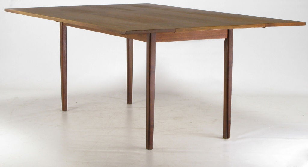 Clean lined and wonderfully grained walnut wood drop leaf dining table from fine furniture manufacturer, Hibriten of NC.  Drop leaves are piano hinged.  When in the up position the table measures 48