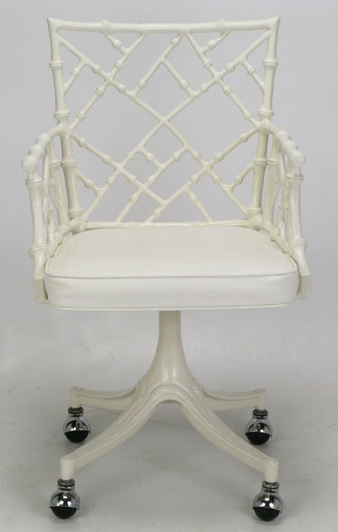 Chinese Chippendale desk chair in cast aluminum. Finished in white satin lacquer, white vinyl seats and chrome ball style casters. Four chairs available, priced individually, would make good seating for an intimate dining area.