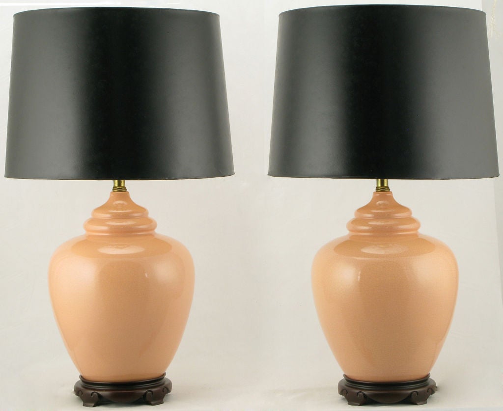 Beautifully finished peach crackle glazed ginger jar form chinoiserie table lamps. The hand carved wood bases are finished in a dark walnut stain. Sold sans shades.
