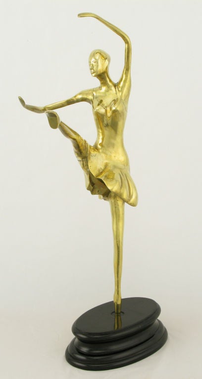 Brass sculpture of a ballerina in motion, on a black lacquered turned wood base.