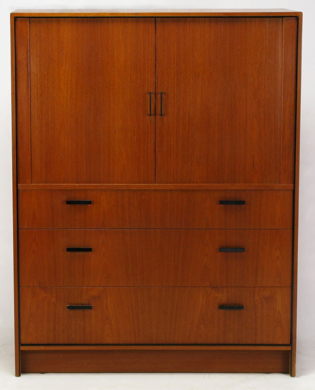 Teak gentleman's dresser or chest, made in Denmark. Two upper doors with black lacquered metal U-shape pulls open and recess to reveal nine drawers, and two shelf compartments. Three large lower drawers with black lacquered bar pulls.<br />
<br